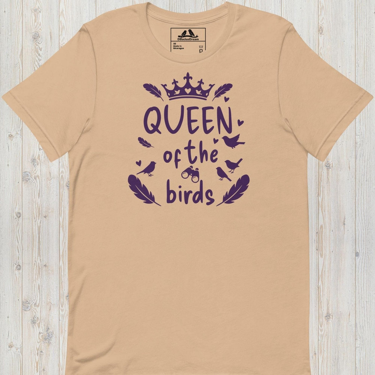 Beige queen of the birds t-shirt with a purple bird graphic, crown design and decorative bird silhouettes
