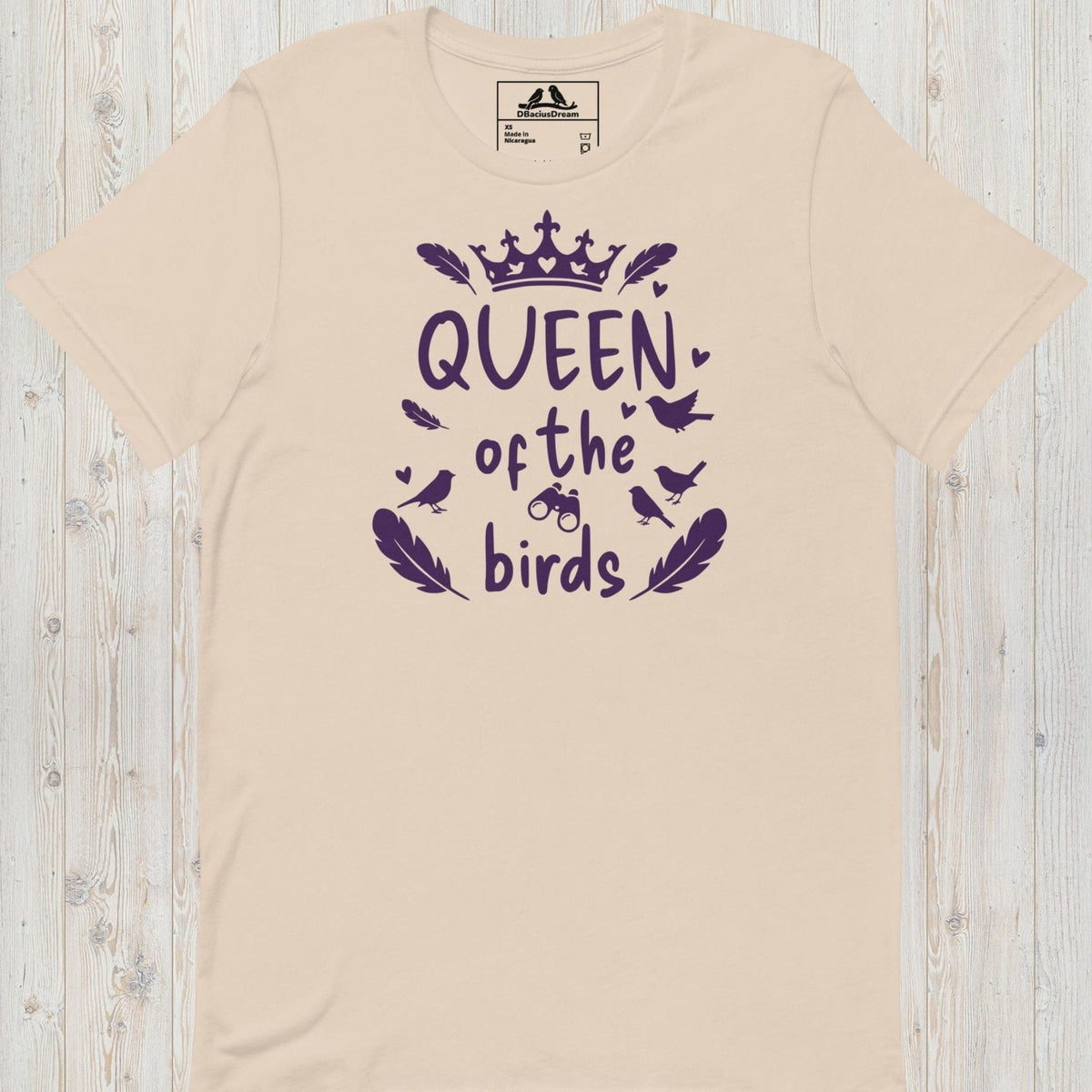 Light beige queen of the birds t-shirt with a purple bird graphic, crown design and decorative bird silhouettes
